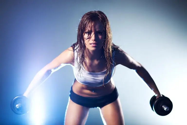 Vrouw in sportkledij met halters tijdens krachttraining – illustratie van spieractivatie en spieropbouw