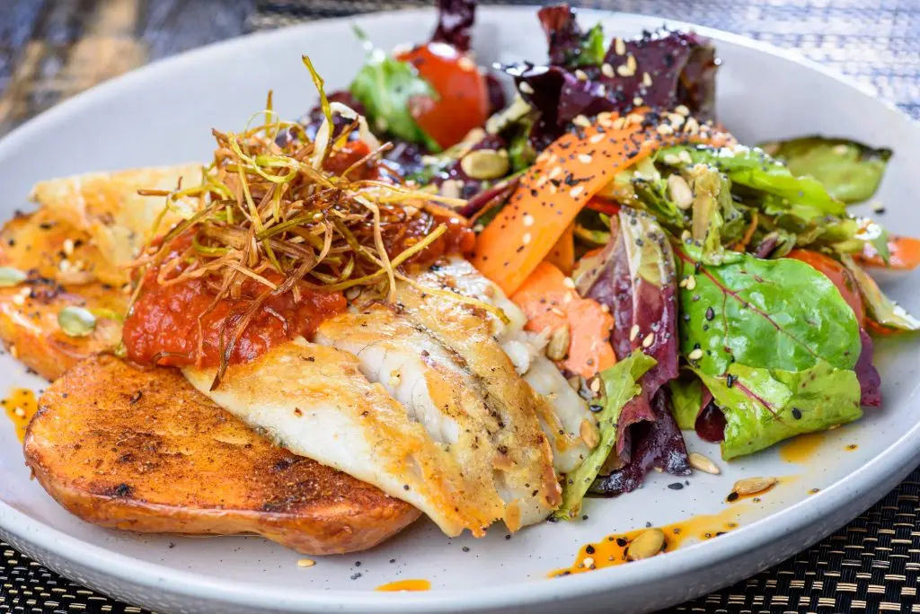 Bord met vis, groenten en zaden als voorbeeld van samenhang tussen plantaardige en dierlijke voeding