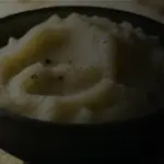 Donkere close-up van aardappelpuree in een zwarte kom.